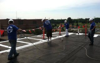 A team of contractors prepare a single-ply roof for product application.