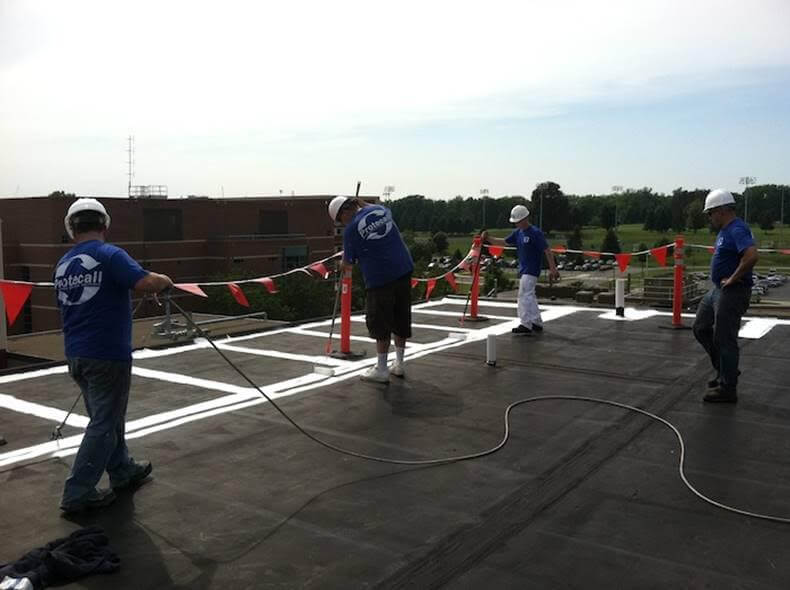 A team of contractors prepare a single-ply roof for product application.