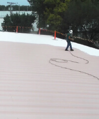 Inland's SEBS roof coating is sprayed onto a metal roofing substrate.