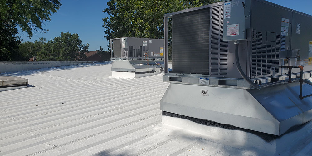 Roof featuring white metal roof coating and two air conditioners