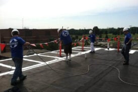 A team of contractors prepare a single-ply roof for product application.
